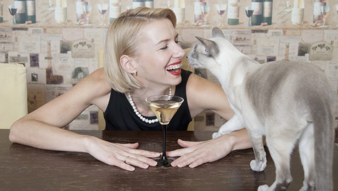 Frau trinkt Wein in der Nähe von Katze