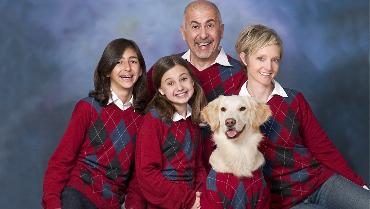 Humorvolles Familienporträt mit Hund des goldenen Apportierhunds alle in den Strickjacken.