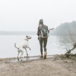 Young woman throwing stick for her dog on misty lakeside