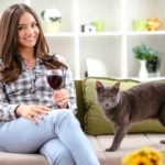 Woman drinking wine on couch with cat on drink wine day