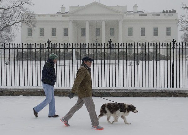 People walk a dog during a snow storm in front of the White House in Washington, DC, March 3, 2014. Snow began falling in the nation