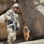 KANDAHAR, AFGHANISTAN - FEBRUARY 28: SPC Daniel Jackson from Centralia, Kansas and his dog Bailey with the 904th Military Police Detachment search through caves looking for weapons caches during a patrol with the U.S. Army
