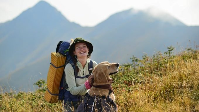 Frau, die in den Bergen mit Hund wandert