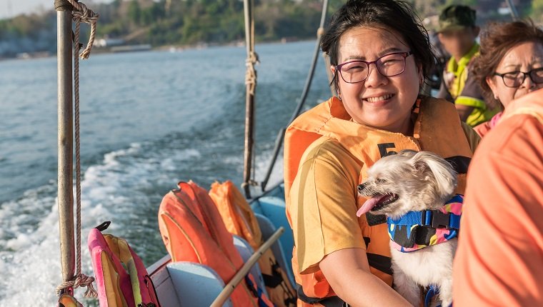 Asiatische Frau und Hund so niedlich gemischte Rasse mit Shih-Tzu, Pommerschen und Pudel, die auf Songkaria Fluss durch langes Schwanzboot mit Sonnenlicht in der Abendzeit segeln, wenn Urlaubsreise zum Entspannen