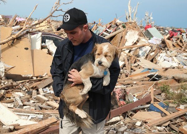 MOORE, OK - MAY 21: Sean Xuereb recovers a dog from the rubble of a home that was destroyed by a tornado on May 21, 2013 in Moore, Oklahoma. The town reported a tornado of at least EF4 strength and two miles wide that touched down yesterday killing at least 24 people and leveling everything in its path. U.S. President Barack Obama promised federal aid to supplement state and local recovery efforts.