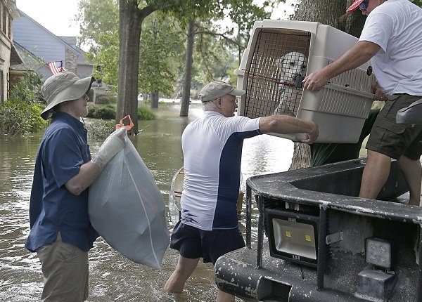 A father and son carry their dog as they evacuate from their homes the flood in Lakeside Estate in Houston, Texas on August 30, 2017. Monster storm Harvey made landfall again Wednesday in Louisiana, evoking painful memories of Hurricane Katrina