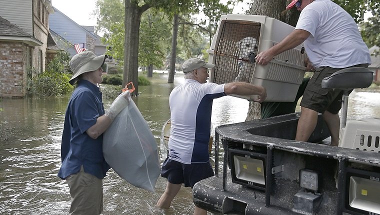 A father and son carry their dog as they evacuate from their homes the flood in Lakeside Estate in Houston, Texas on August 30, 2017. Monster storm Harvey made landfall again Wednesday in Louisiana, evoking painful memories of Hurricane Katrina