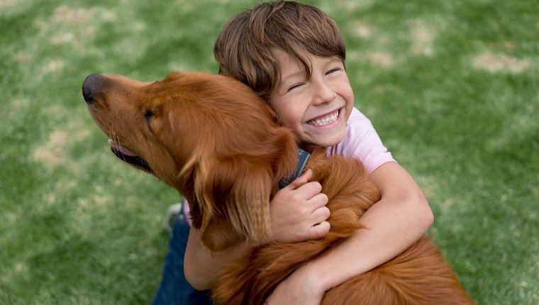 Porträt eines glücklichen Jungen im Freien, der einen schönen Hund umarmt - Lebensstilkonzepte