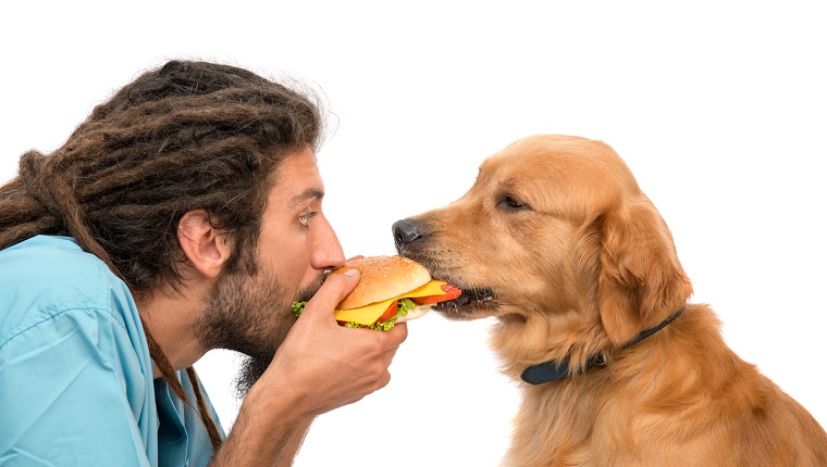 Besitzer und sein Hund essen einen Burger