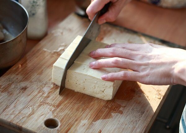 cutting Tofu on the chopping board in Kitchen