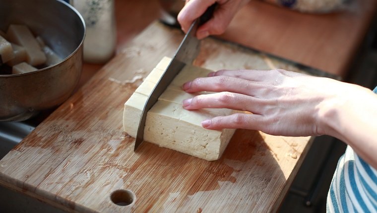cutting Tofu on the chopping board in Kitchen