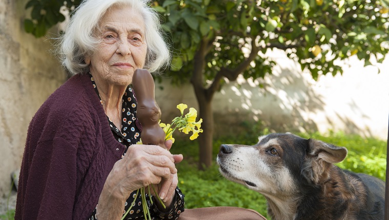 Ältere Frau mit Osterschokoladenhase und Blumen