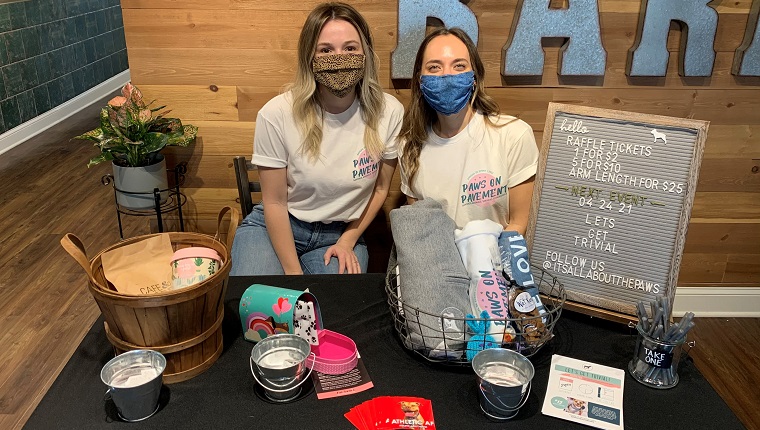 IAATP-Gründerin und Präsidentin Erika (rechts) und IAATP-Freiwillige (links) besetzten die Verlosung, die zu kaufenden Gegenstände und das Werbegeschenk für Goodie-Bags im Cafe & Barr für den Drop-In-Teil des 5-km-Events.