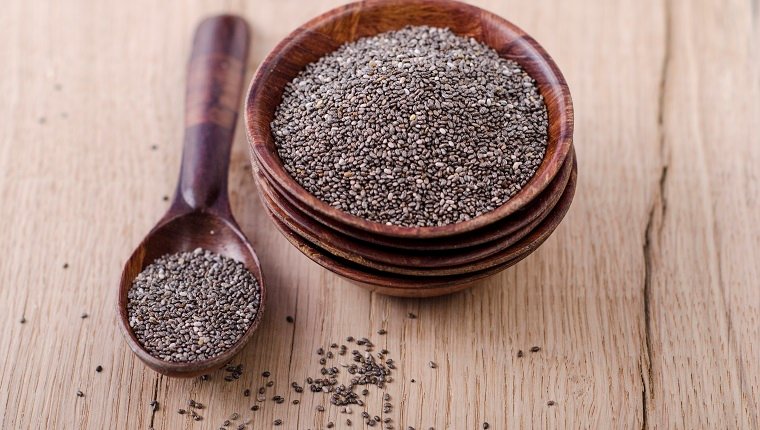 Stack of wooden bowl with chia seeds and wooden spoon on wood