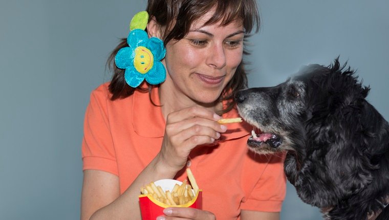 Frau, die Pommes Frites mit ihrem Hund im Tessin Schweiz isst.