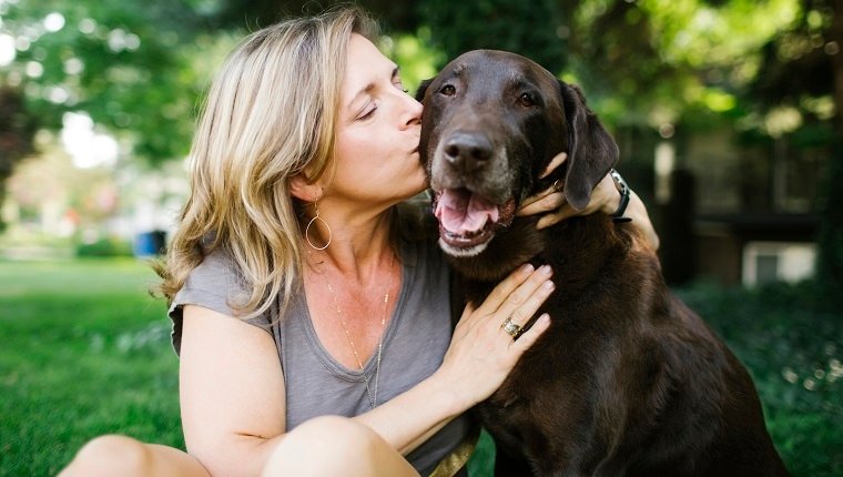 Porträt der Frau, die Labrador Retriever küsst