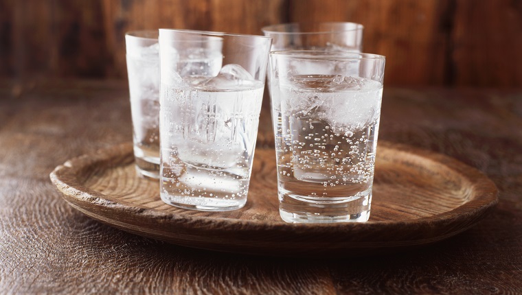 Sprudelwasser im Trinkglas mit Eis auf Vintage-Holzplatte
