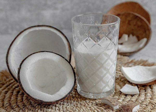Opened coconuts, glass of homemade coconut milk and coconut chunks