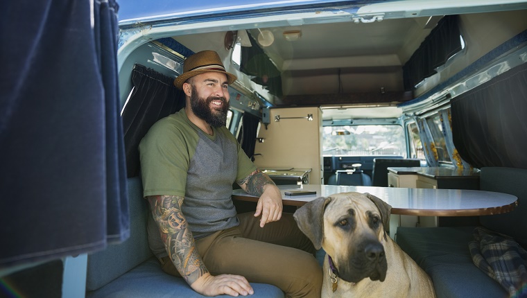 Lächelnder bärtiger Mann mit Hund im Wohnmobil