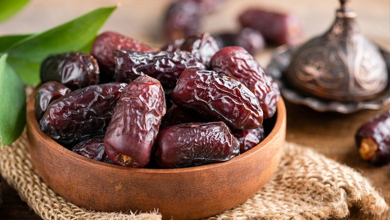 Dried medjool dates in wooden bowl. Islamic culture, Ramadan holiday concept