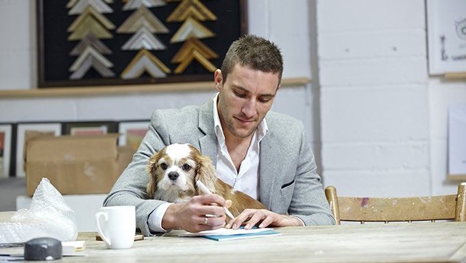 Mann schreibt mit Hund auf dem Schoß