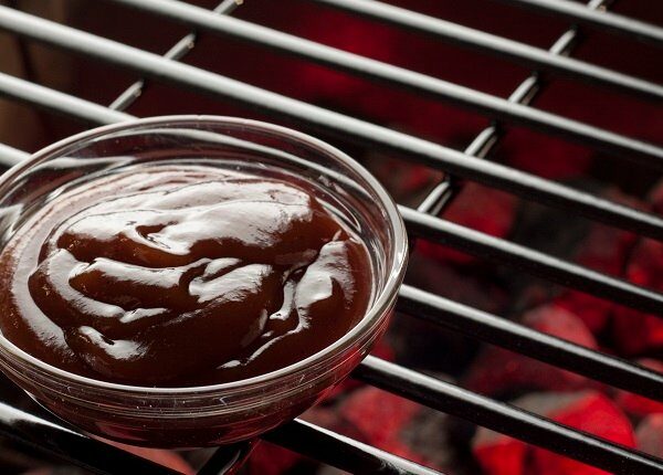 A bowl of BBQ sauce on the grill.