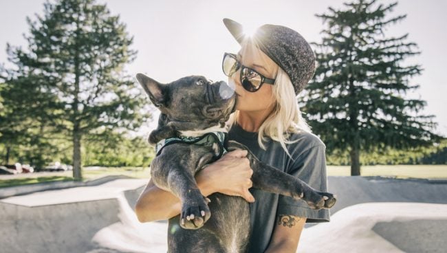 Alleinstehende Frau im Skatepark küsst ihren Hund